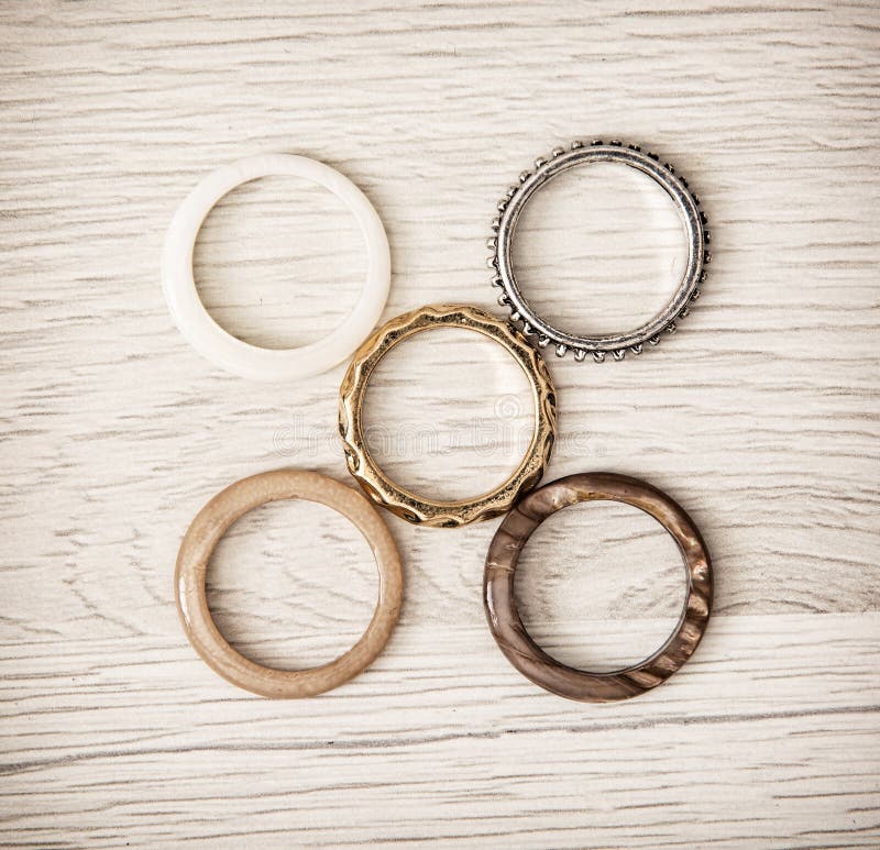 Women's rings arranged on the wooden background. Costume jewelry. Women's rings arranged on the wooden background. Costume jewelry.
