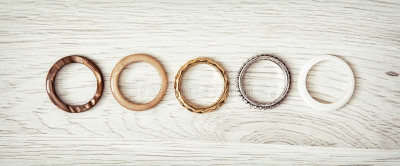 Women's rings arranged in a row on the wooden backround. Costume jewelry. Women's rings arranged in a row on the wooden backround. Costume jewelry.