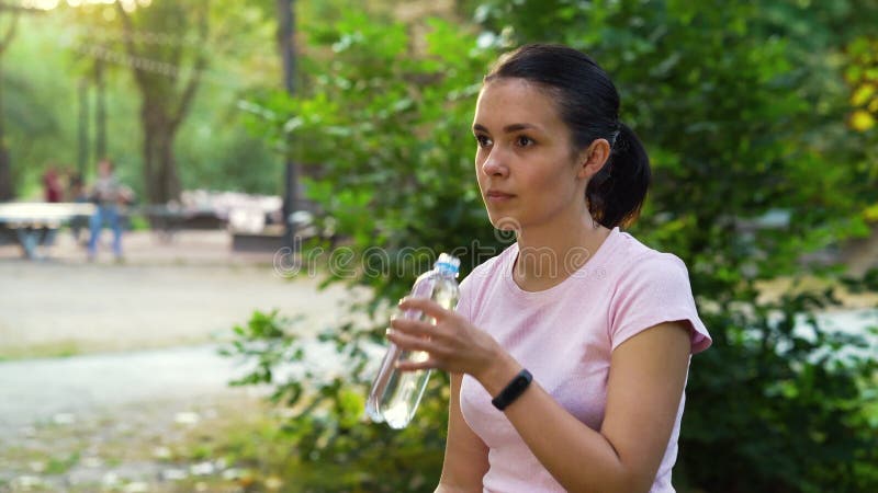 Kobieta pijąca wodę po joggingu w parku