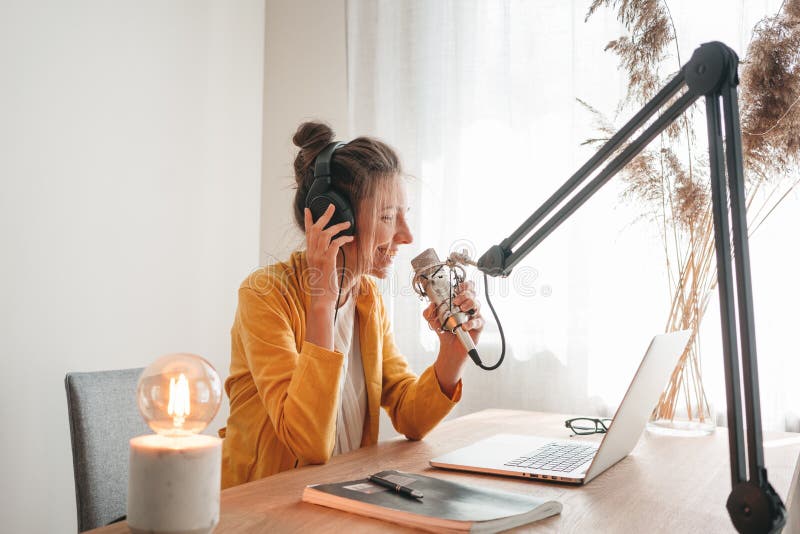 Kobieta podcaster nagrywająca swój podcast za pomocą mikrofonu i laptopa w swoim małym domowym studio telewizyjnym zdjęcie royalty free