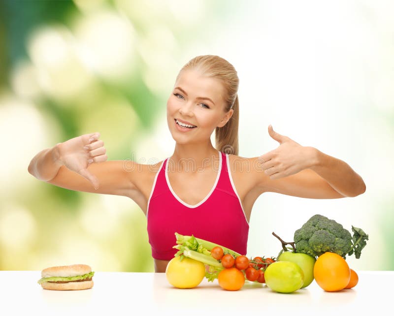 Fitness, healthcare and diet concept - smiling woman with fruits and hamburger showing good and bad signs. Fitness, healthcare and diet concept - smiling woman with fruits and hamburger showing good and bad signs