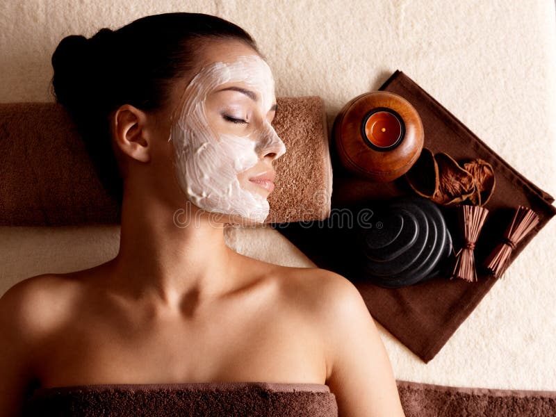 Kobieta relaksuje z twarzową maską na twarzy przy piękno salonem