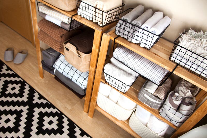 Spring cleaning of closet. Vertical tidying up storage. Neatly folded bed sheets in the metal black baskets for wardrobe. Nordic style. Spring cleaning of closet. Vertical tidying up storage. Neatly folded bed sheets in the metal black baskets for wardrobe. Nordic style