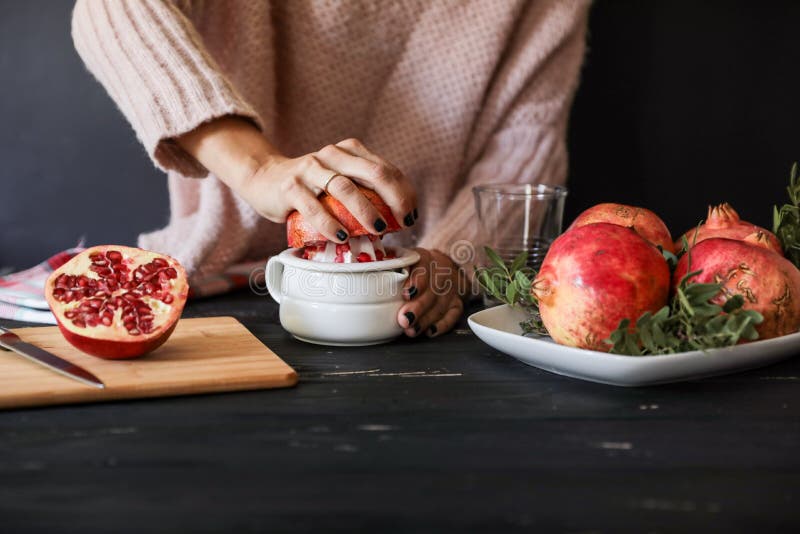 Kobieta robi świeżemu granatowa sokowi na czarnym drewnianym tle używać ręki juicer blisko składników obrazy royalty free Kobieta robi świeżemu granatowa sokowi na czarnym drewnianym tle używać ręki juicer blisko składników obrazy royalty free