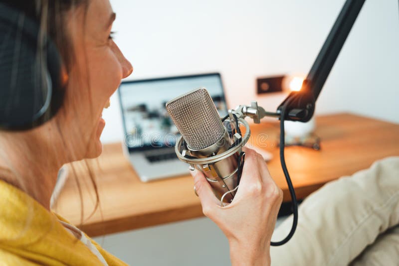 Kobieta siedzi na stole i nagrywa podcast w jego małym przytulnym studio radiowym obrazy stock