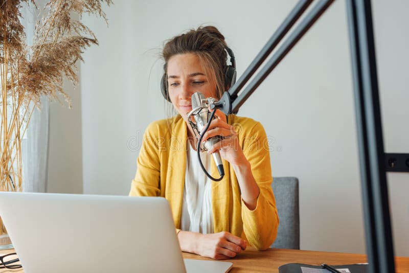 Kobieta siedzi na stole i nagrywa podcast w jego małym przytulnym studio radiowym zdjęcie royalty free