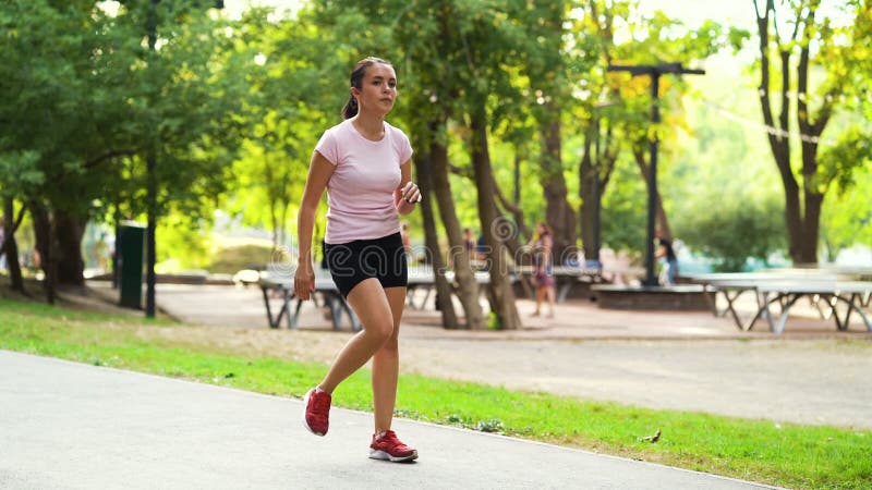 Kobieta sportowa biegnąca na miejscu i rozgrzewająca stopy w parku