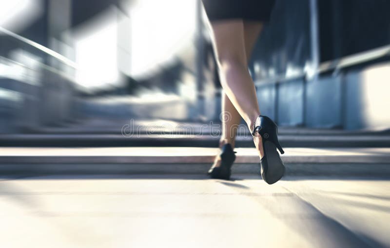Kobieta uciekająca lub chodząca szybko z wysokimi obcasami na ulicy miejskiej Zajęty biznesmen w pośpiechu Szybkie opóźnienia w p