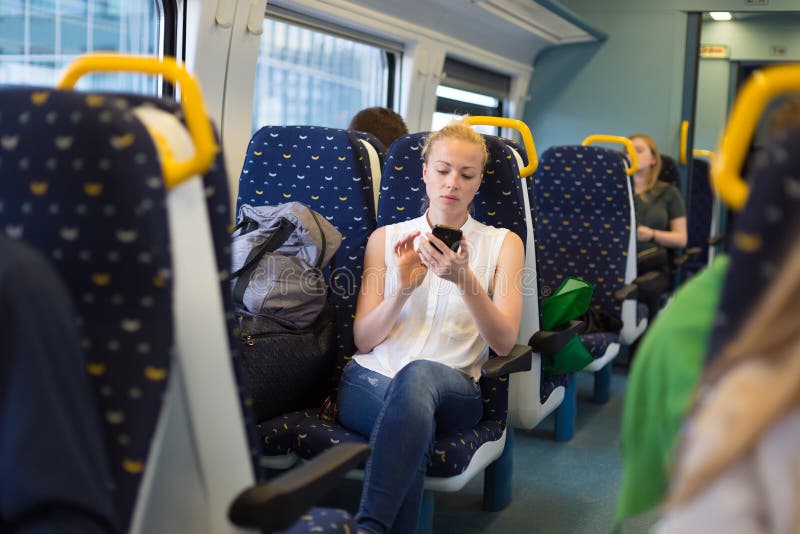Kobieta używa telefon komórkowego podczas gdy podróżujący pociągiem