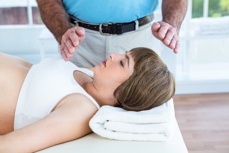 Kobieta w ciąży odpoczywa podczas gdy męski terapeuta spełniania reiki zdjęcia stock Kobieta w ciąży odpoczywa podczas gdy męski terapeuta spełniania reiki zdjęcia stock