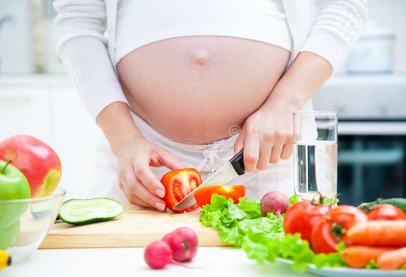 Pregnant woman in kitchen making salad. Pregnant woman in kitchen making salad
