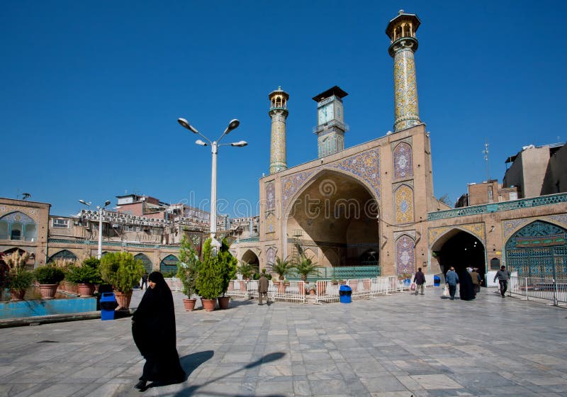 Kobieta w hijab śpieszy się od imama Homeini meczetu budującego w 18th z dwa minaretami wcześnie obrazy royalty free Kobieta w hijab śpieszy się od imama Homeini meczetu budującego w 18th z dwa minaretami wcześnie obrazy royalty free