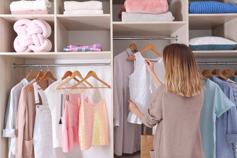 Woman choosing outfit from large wardrobe closet with stylish clothes and home stuff. Woman choosing outfit from large wardrobe closet with stylish clothes and home stuff