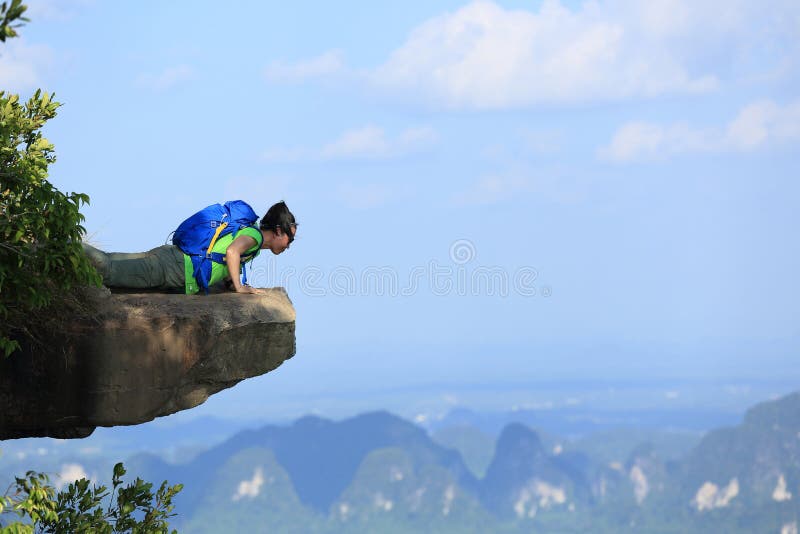 Kobieta wycieczkowicz patrzeje w dół na halnego szczytu falezie