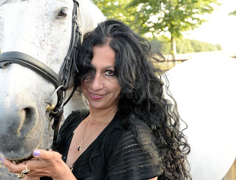 A mature black haired woman with a white horse. A mature black haired woman with a white horse.