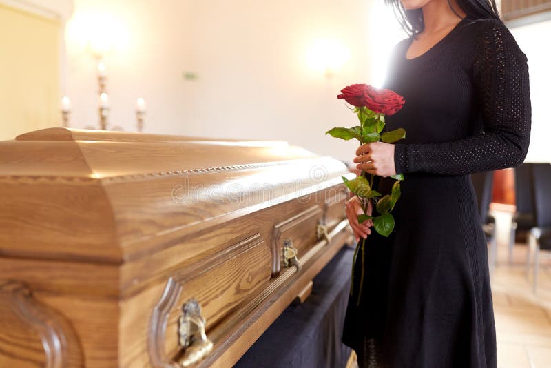 Kobieta z czerwonymi różami i trumną przy pogrzebem