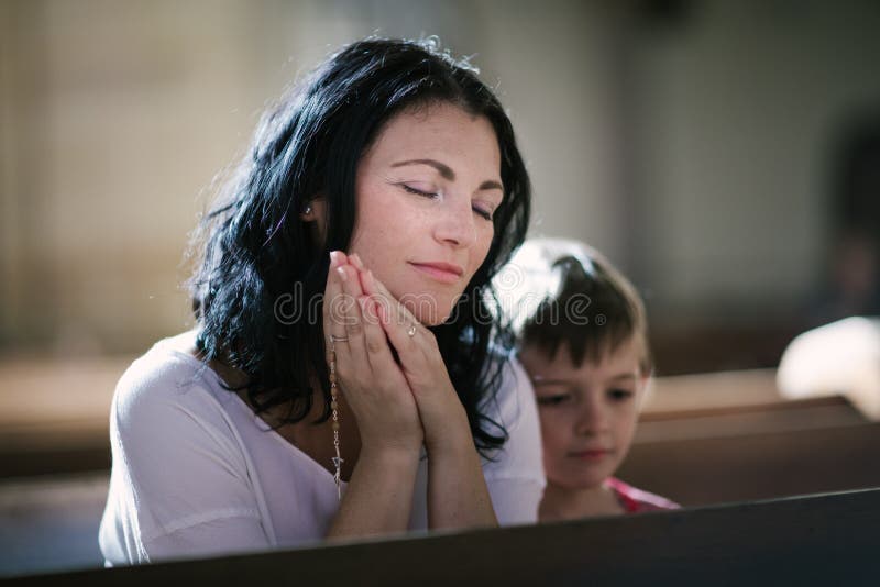 Beautiful women with her son praying in the church. Beautiful women with her son praying in the church