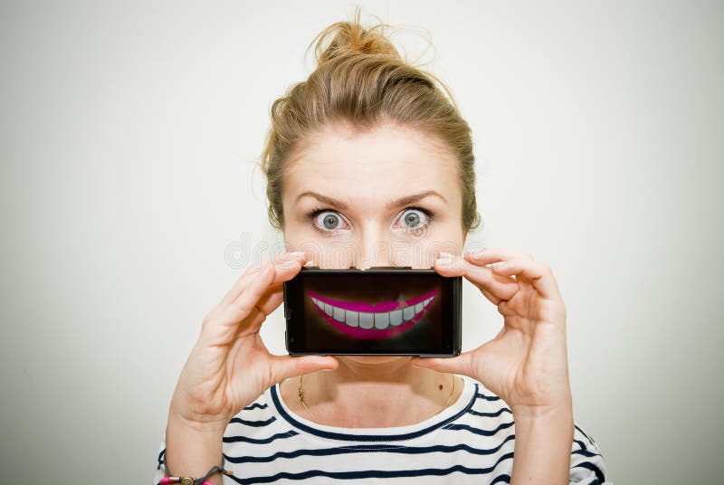 Young scared woman holding smartphone over her mouth with animated smile. Young scared woman holding smartphone over her mouth with animated smile.