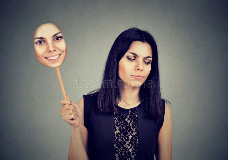 Young woman with sad expression taking of a mask expressing cheerfulness. Young woman with sad expression taking of a mask expressing cheerfulness