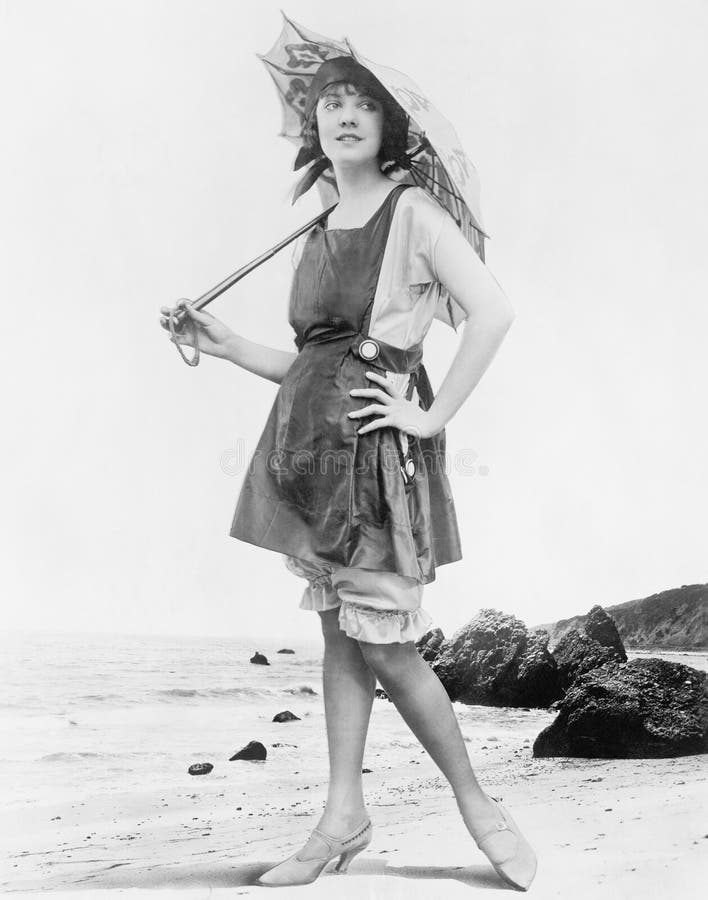 Kobieta z słońce kostiumem kąpielowym przy plażą i parasolem (Wszystkie persons przedstawiający no są długiego utrzymania i żadny