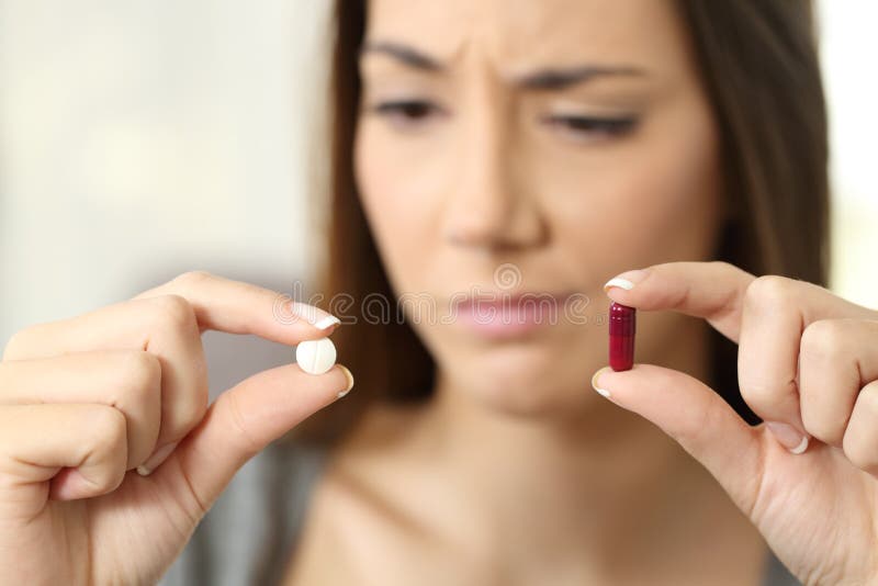 Portrait of a woman wondering about pill or capsule in a house interior. Portrait of a woman wondering about pill or capsule in a house interior