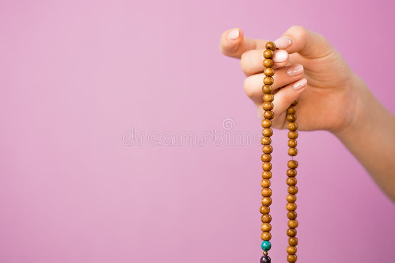 Woman, lit hand close up, counts Malas, strands of gemstones beads used for keeping count during mantra meditations. Woman, lit hand close up, counts Malas, strands of gemstones beads used for keeping count during mantra meditations.