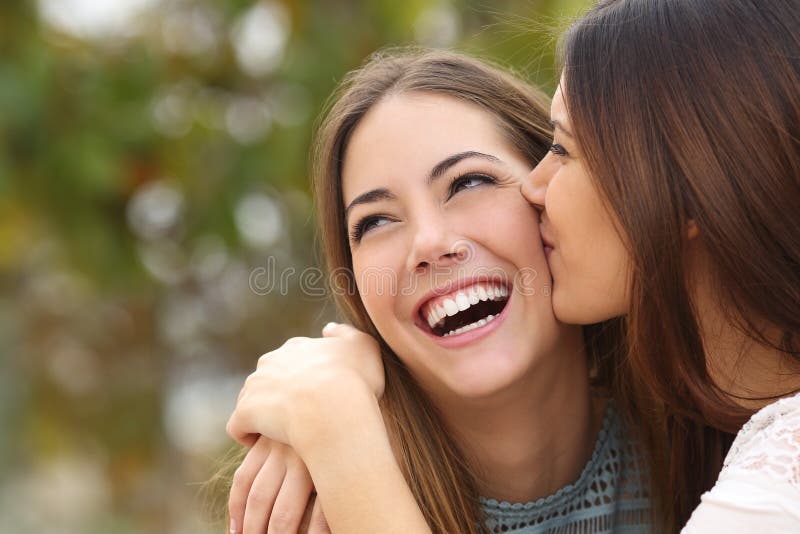 Kobieta śmia się z perfect zębami podczas gdy przyjaciel całuje ona