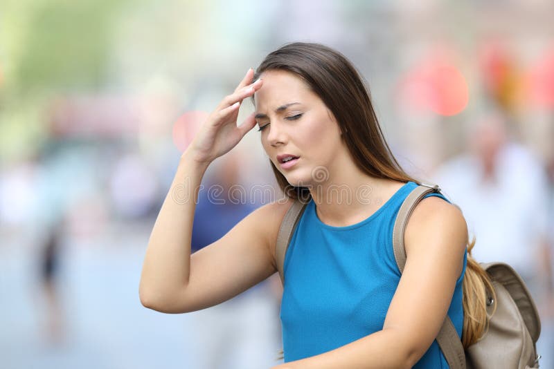Single woman suffering headache outdoors in the street. Single woman suffering headache outdoors in the street
