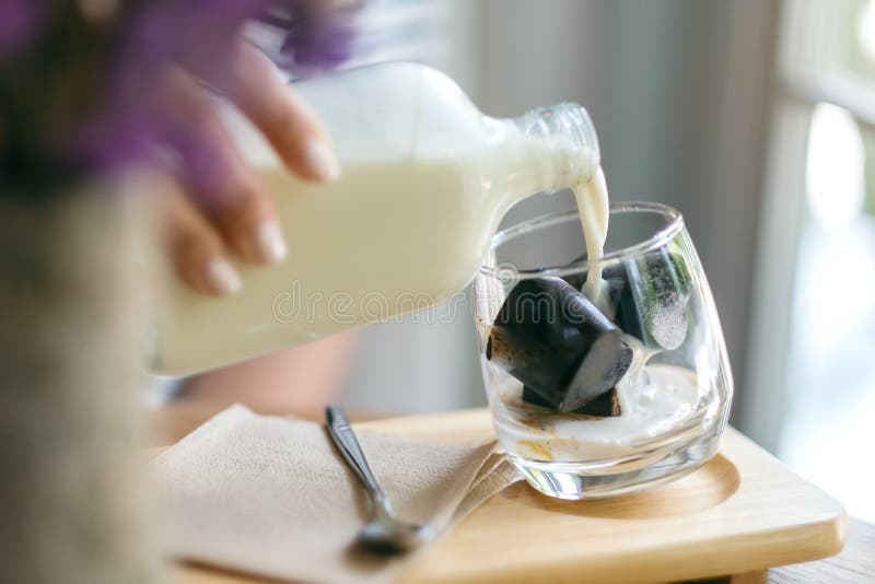 Kobiety dolewania mleko w szkło kostka lodu kawa w kawiarni zdjęcia stock Kobiety dolewania mleko w szkło kostka lodu kawa w kawiarni zdjęcia stock