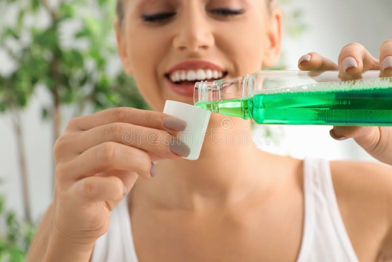 Kobiety dolewania mouthwash od butelki w nakrętkę zdjęcie royalty free Kobiety dolewania mouthwash od butelki w nakrętkę zdjęcie royalty free