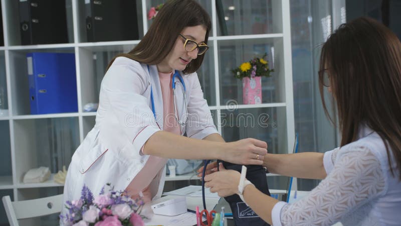 Kobiety lekarka mierzy naciska pacjent w biurze przy kliniką i pisze jej przydziale