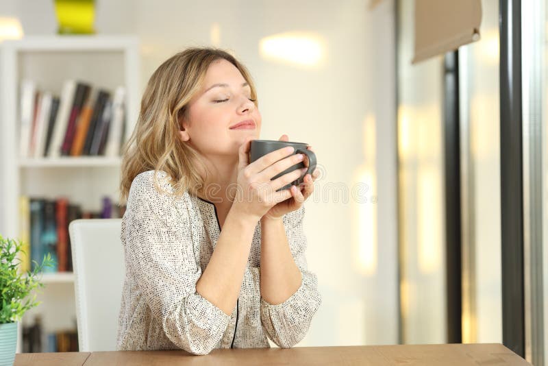 Kobiety oddychanie trzyma kawowego kubek w domu