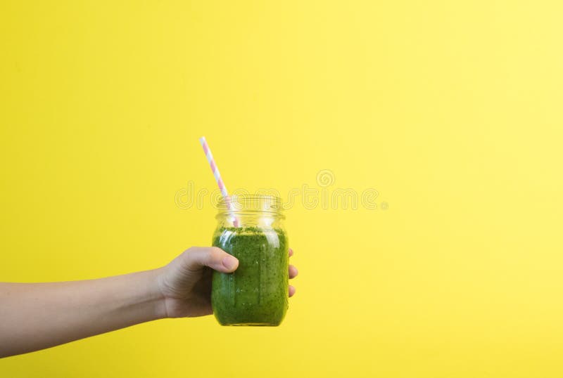 Kobiety ręki mienia smoothie potrząśnięcie przeciw barwionej ścianie Pić zielonego zdrowego smoothie pojęcie obraz stock Kobiety ręki mienia smoothie potrząśnięcie przeciw barwionej ścianie Pić zielonego zdrowego smoothie pojęcie obraz stock