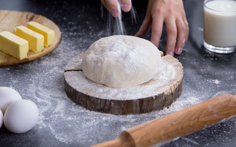 Kobiety tryskaczowa mąka nad świeżym ciastem na kuchennym stole obrazy royalty free Kobiety tryskaczowa mąka nad świeżym ciastem na kuchennym stole obrazy royalty free