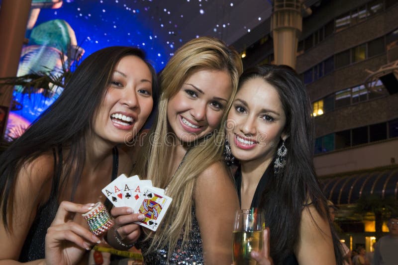 Portrait of happy female friends holding casino chips, playing cards and champagne glass. Portrait of happy female friends holding casino chips, playing cards and champagne glass