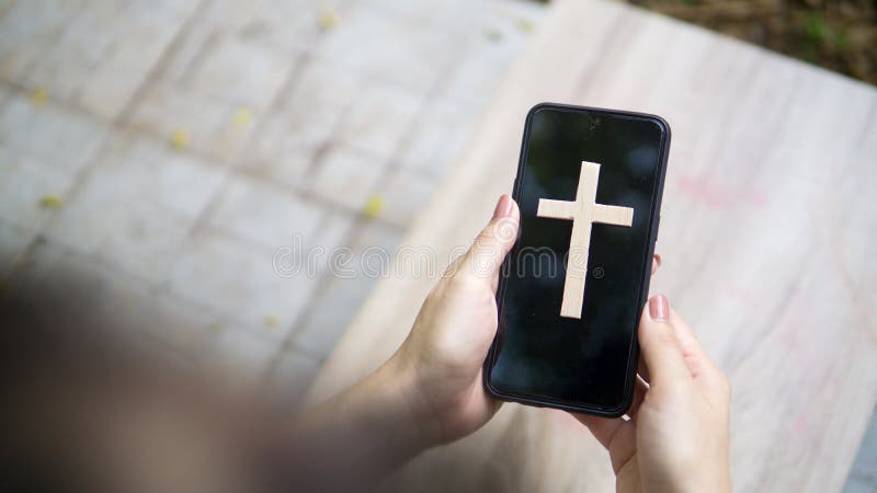 Woman`s hand with cross in screen mobile phone. Concept of hope, faith, christianity, religion, church online. Woman`s hand with cross in screen mobile phone. Concept of hope, faith, christianity, religion, church online.