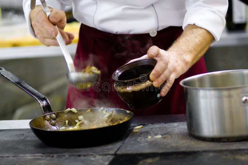 Cook on kitchen adds meat dish. Cook on kitchen adds meat dish