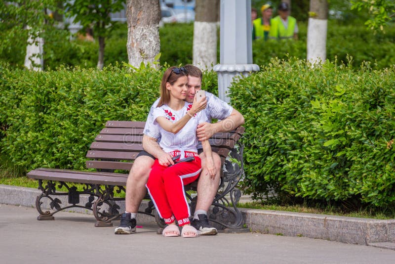 Kochająca para siedzi na ławce i robi selfies zdjęcia stock Kochająca para siedzi na ławce i robi selfies zdjęcia stock