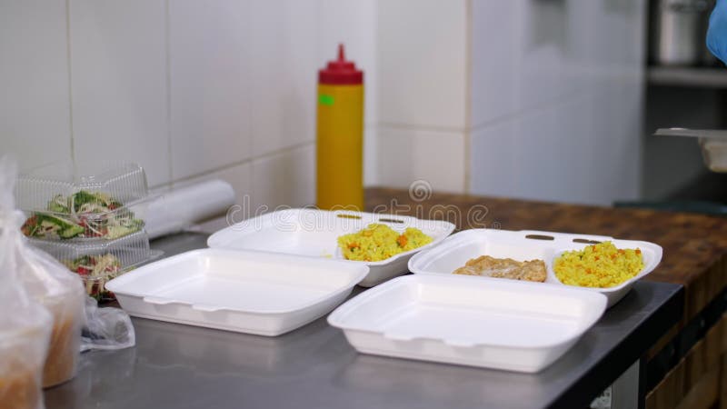 Kochen. Nahaufnahmefreiwilliger in den Schutzhandschuhen Verpackung freie warme Mahlzeiten in den an die Armen zu liefernden Lunch