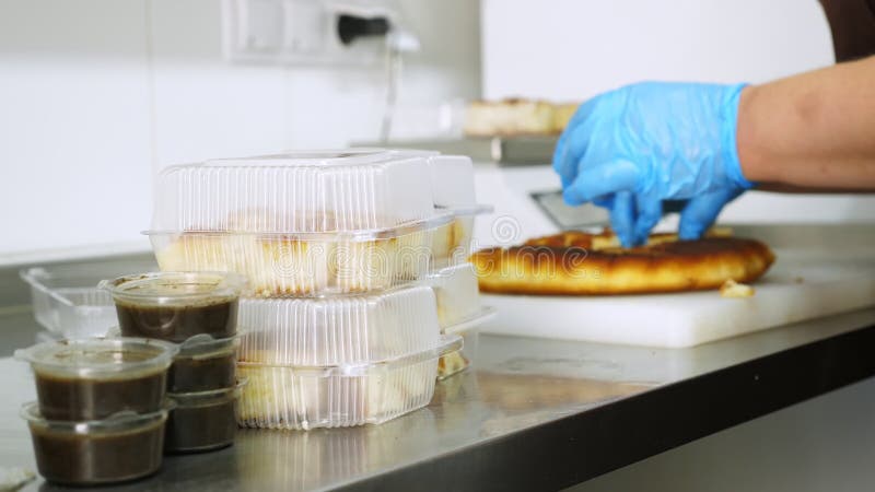 Kochen. Verpackung freiwillige Küchearbeitskraft der Nahaufnahme in den Schutzhandschuhen freies geschnittene Brot in den Lunchbox