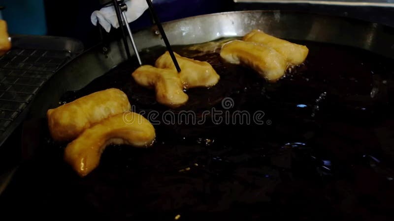 Kock som gör dig till varm stekpanna på den lokala marknaden, traditionell friterad deg mat. chinese cruller