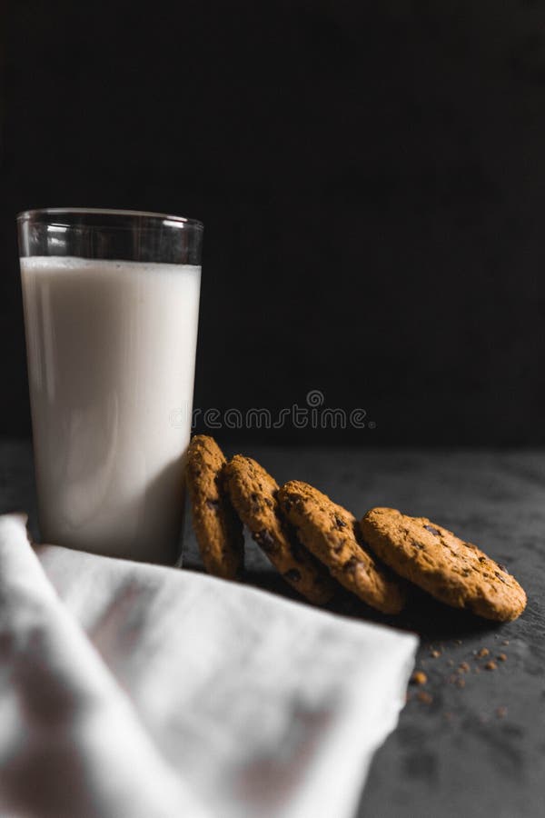 Koekjes met chocoladeschepen en melk met een donkere achtergrond royalty-vrije stock afbeelding Koekjes met chocoladeschepen en melk met een donkere achtergrond royalty-vrije stock afbeelding