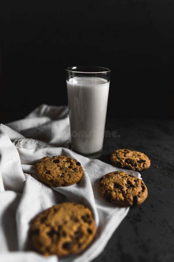 Koekjes met chocoladeschepen en melk met een donkere achtergrond stock fotografie Koekjes met chocoladeschepen en melk met een donkere achtergrond stock fotografie