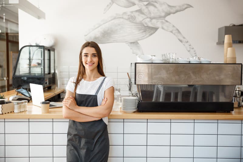 Koffie Bedrijfseigenaar Concept - Portret van gelukkige aantrekkelijke jonge mooie Kaukasische barista in schort die glimlachen b stock foto Koffie Bedrijfseigenaar Concept - Portret van gelukkige aantrekkelijke jonge mooie Kaukasische barista in schort die glimlachen b stock foto