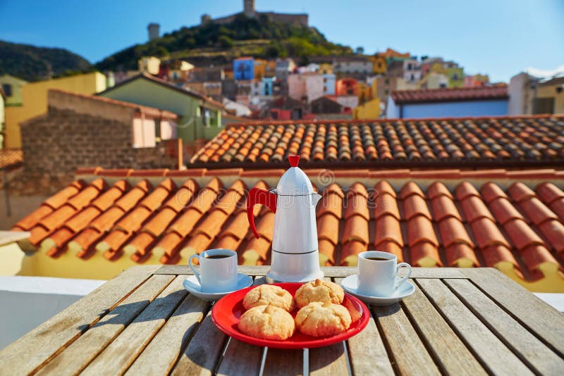 Koffie en Italiaanse snoepjes met mening aan Bosa-dorp, Sardinige, Italië stock foto Koffie en Italiaanse snoepjes met mening aan Bosa-dorp, Sardinige, Italië stock foto