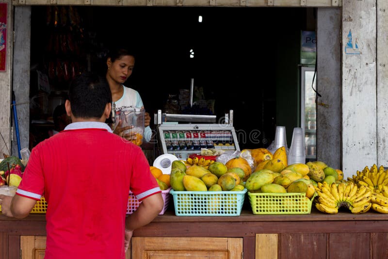 Koh Rong-eiland, Kambodja - 6 April 2018: de Khmer mens koopt tropisch fruit in lokale opslag Mango en banaan op lokale winkel stock afbeelding Koh Rong-eiland, Kambodja - 6 April 2018: de Khmer mens koopt tropisch fruit in lokale opslag Mango en banaan op lokale winkel stock afbeelding