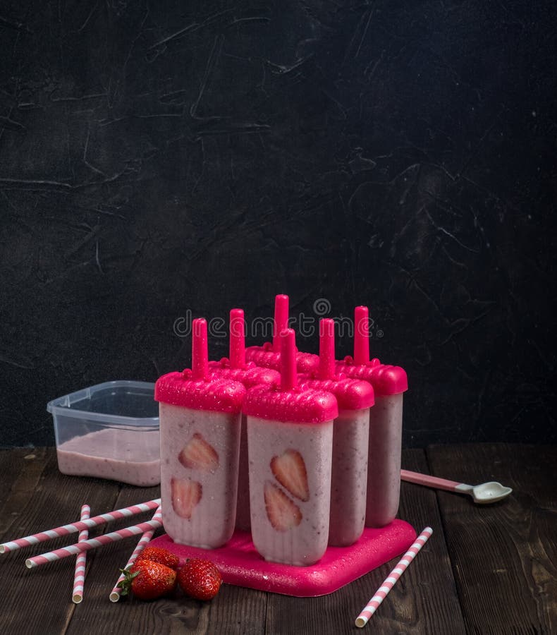 kokende eigengemaakte maaltijd: fruitijs in vormen voor het vullen met stukken aardbeien op een donkere achtergrond stock fotografie kokende eigengemaakte maaltijd: fruitijs in vormen voor het vullen met stukken aardbeien op een donkere achtergrond stock fotografie