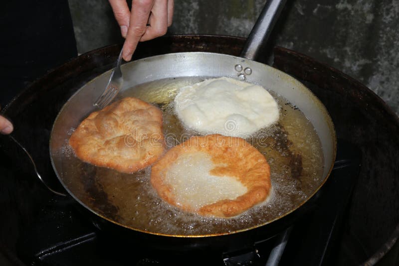 Kokhanden terwijl het koken van gebraden die fritters in het koken wordt ondergedompeld oi royalty-vrije stock afbeeldingen Kokhanden terwijl het koken van gebraden die fritters in het koken wordt ondergedompeld oi royalty-vrije stock afbeeldingen