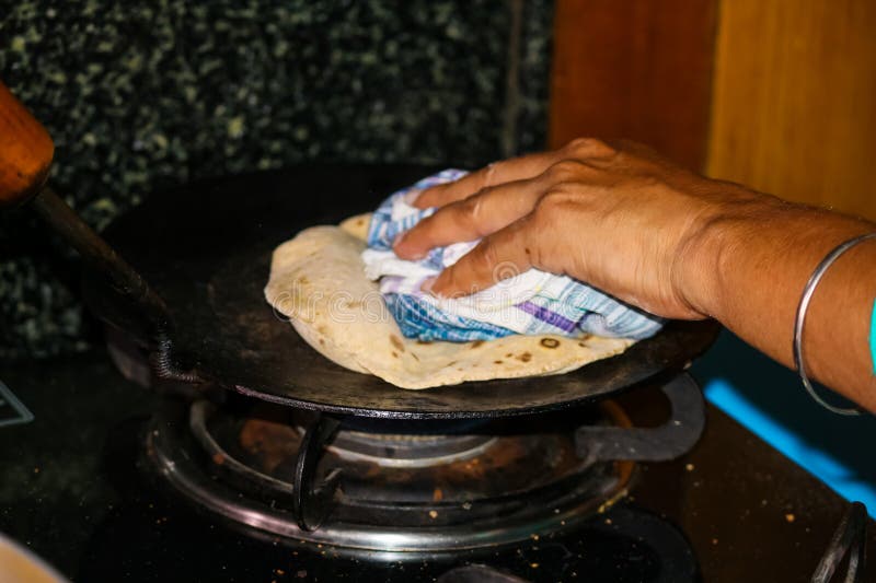 Kokning på en gasbuske i köket hemma hos indian vete chapati pancakes. arkivfoton