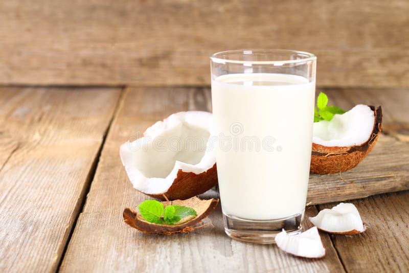 Kokosowy i kokosowy mleko w szkle, mennica na drewnianym starym stole